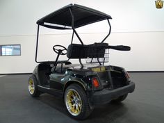 a black golf cart with a basket on the back and wheels is parked in a large room