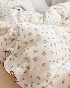 an unmade bed with white linens and flowers on the comforter is shown