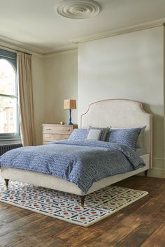 a bedroom with a bed, dresser and window in the corner that has a rug on the floor