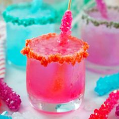 three glasses filled with pink, blue and red drinks on top of a white table