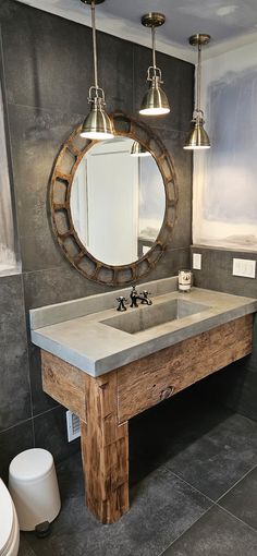 a bathroom with a sink, mirror and lights on the wall next to two toilets