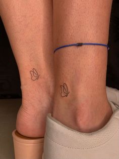 two people with tattoos on their legs and one has a blue string around the ankle