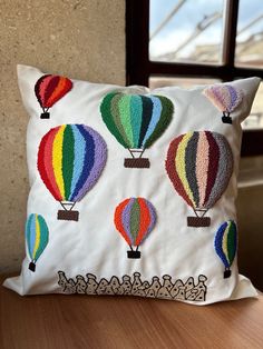 a pillow with colorful hot air balloons on it sitting on a table next to a window