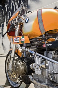 an orange motorcycle parked next to a wall