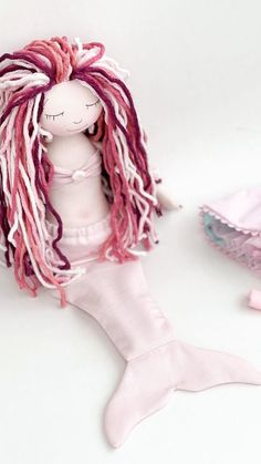 a doll with pink and red dreadlocks sitting next to it's body