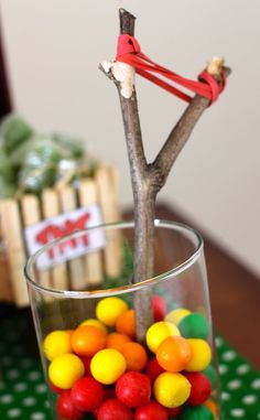 a glass filled with candy sitting on top of a table next to a tree branch