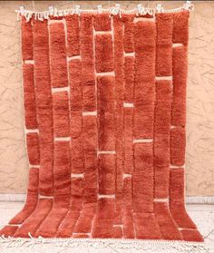 an orange rug with squares and fringes on the floor in front of a wall