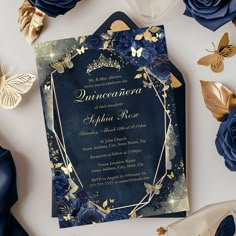 a blue wedding card with gold foil flowers and butterflies on it, surrounded by other paper decorations