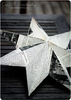 an origami star is sitting on top of a wooden table with newspaper pages