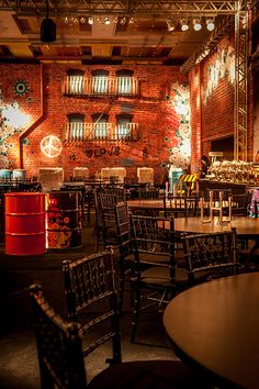 an empty restaurant with tables and chairs in front of a red brick wall that has graffiti on it