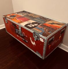 an old trunk is sitting on the floor in front of a wall with posters all over it