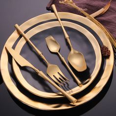 a gold plate with utensils and spoons on it, next to a purple napkin