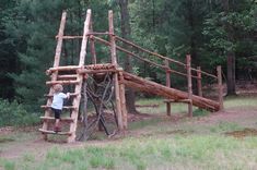 a little boy standing on top of a wooden slide