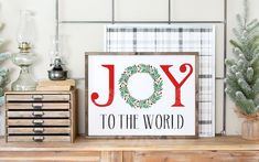 a wooden sign that says joy to the world on top of a dresser with christmas decorations