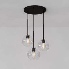 three clear glass globes hanging from a ceiling light fixture with black metal fittings