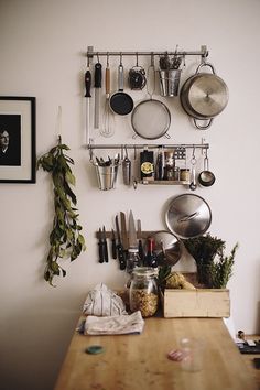 a kitchen with pots and pans hanging on the wall next to a cutting board