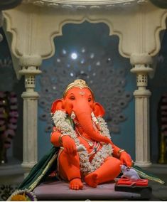 an elephant statue sitting on top of a table in front of a wall and pillars