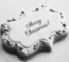 a white christmas ornament with black and silver beads on the edges that says merry christmas