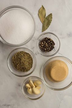 the ingredients to make this recipe include spices, sugar, and seasonings in glass bowls on a white marble countertop