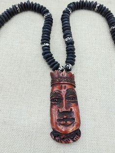 The African King mask pendant is a hand carved piece. The piece has lots of amazing detail. The beads are a mix of handmade glass and black hand painted beads. The necklace is beaded on a thick cord and closes with a large clasp.  If you have any questions please feel free to contact us at anytime.  Clean with soft cloth. The African Carved pendant is approximately 3.10 inches long. The necklace is approximately 22 inches long. If you have any questions please feel free to contact us at anytime. Keep clear of oils, water and chemicals. Wipe off with soft cloth to clean. The piece is one of a kind. We love to use unique pieces, handmade and carved, from vintage to new. If you have any questions please feel free to contact us at anytime. Our products are not intended for babies or children a Handmade Black Necklaces For Festivals, Hand-strung Black Jewelry For Festivals, Handmade Black Necklace For Festivals, Artisan Black Jewelry For Festivals, Black Hand-strung Jewelry For Festivals, Black Beaded Necklaces With Large Beads For Festivals, Black Beaded Necklace With Large Beads For Festivals, Artisan Black Beaded Necklaces For Festivals, Handmade Black Necklaces For Rituals