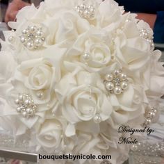 a bridal bouquet with white flowers and pearls on the bottom is sitting on a table