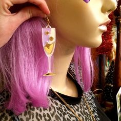 a mannequin head with pink hair and gold earrings on it's face