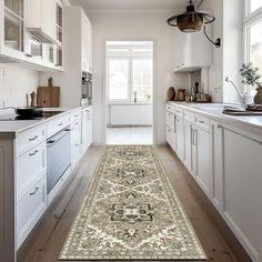 a large rug in the middle of a kitchen with white cupboards and drawers on both sides