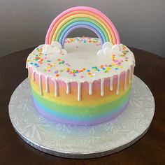 a rainbow cake with white icing and sprinkles