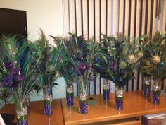 several vases filled with purple flowers and green leaves on a wooden table in front of a window