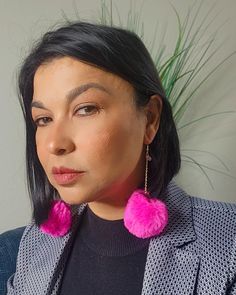 a woman with black hair wearing pink earrings