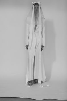 a woman in white is standing with her hands on her hips and wearing a veil over her head