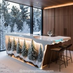 a kitchen island with trees on it in front of a large window overlooking the snow covered forest