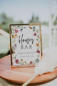 a card and gifts sign sitting on top of a wooden table next to a white feather