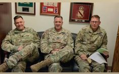 three men in uniform are sitting on a couch