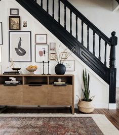 a living room with an area rug, wooden furniture and pictures hanging on the wall