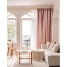 a living room with pink drapes and curtains on the windowsills, a white couch in front of a coffee table