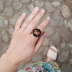 a woman's hand with a flower ring on it, next to her feet