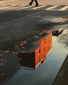 a person walking across a street next to a puddle