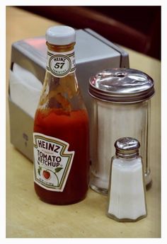 a bottle of heinzz tomato ketchup next to a salt and pepper shaker