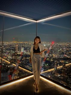 a woman standing on top of a tall building in front of a cityscape