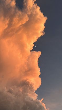 an airplane is flying in the sky with clouds and a half moon behind it at sunset