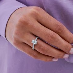 a close up of a person's hand wearing a ring with an emerald stone