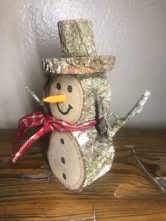 a snowman made out of wood with a red ribbon around it's neck