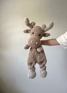 a crocheted stuffed animal is being held by someone's hand in the air