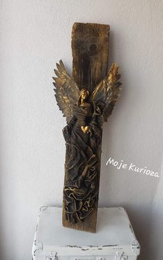 a wooden statue with an angel on it's back sitting on top of a white box