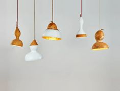 five hanging lights in various shapes and sizes on a white wall above a dining room table