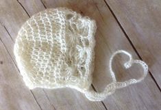 a crocheted white hat with a heart on the side sitting on a wooden floor