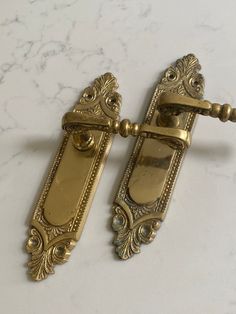 two antique brass door handles on a marble surface