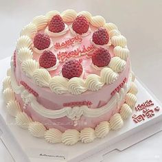 a birthday cake decorated with raspberries and white frosting on a card board