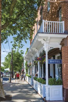 people walking down the sidewalk in front of a hotel